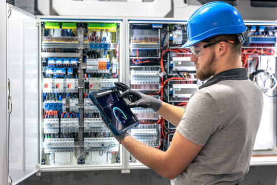 Electrician with tablet. Working at switchboard. Digital tools in use. - Powered by Adobe