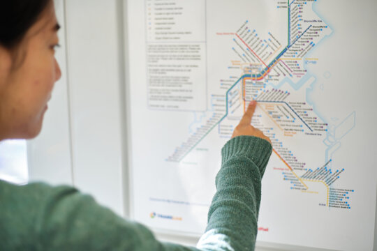 Young Asian woman pointing on the train map focus on arm