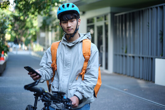 Young Asian delivery guy with his bicycle on the street