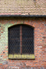 Old arched window. Iron bars. Brick wall.