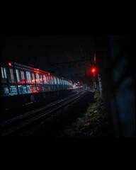 Night motion blur of a train speeding through a city railway station with car lights streaking on the urban road