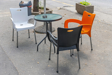 Glass Table With Plastic Chairs Set at Street Pavement