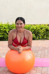 Latin woman doing pilates exercises with swiss ball outdoors
