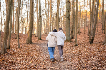 Fototapeta premium Two female friends on a walk in the forest. Friends walking through the forest. People in nature.