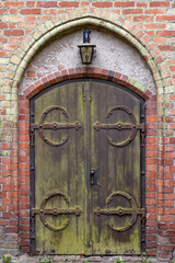 Vintage wooden door. Rusty wrought hinges. Gothic entry arch.