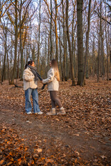 Fototapeta premium Two female friends on a walk in the forest. Friends walking through the forest. People in nature.