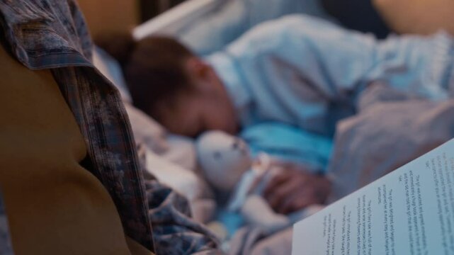 Rack focus of young African American father reading book to his little daughter laying under blanket hugging her favorite toy and listening to bedtime stories spending cozy evening together