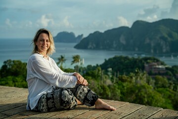A girl in a white shirt sits on the terrace of the observation deck overlooking the panorama of Koh...