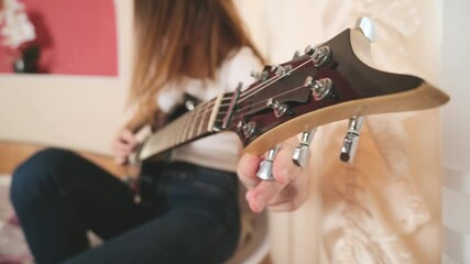 Guitar fretboard: creative woman musician plays the guitar. The musician plays a musical instrument, close-up, hands in the frame.