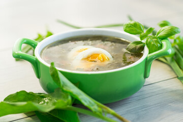 Traditional Ukrainian sorrel borscht with egg on light wooden table