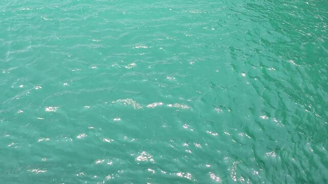 Background view of the sunlit waters of the North Euboean Gulf, shimmer with gentle ripples, revealing the historic tidal currents of the Evripos Strait in Chalkis, Euboea, Greece.