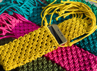 A vibrant close-up of hand-knitted macramé smartphone bags.