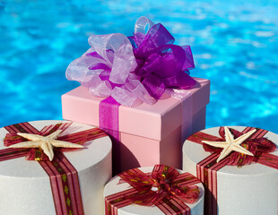 Three elegantly wrapped gifts, one square and two round, decorated with bows and ribbons, set...