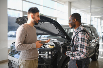 Man on the result of the work of a mechanic. The client evaluates the repair of the car by a...