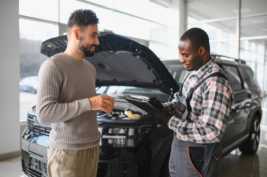 A satisfied client takes his repaired car to the mechanic. Car service station