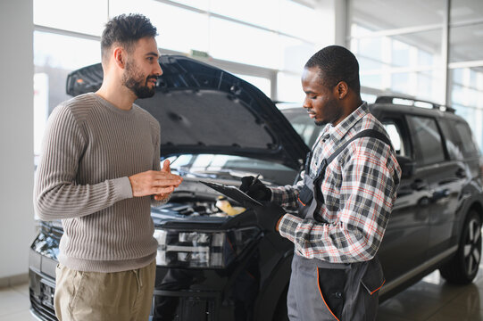 Mechanic, car servicing at garage - concept of timely customer service, car maintenance and deal agreemnet