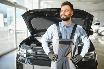 Car repair shop. Young adult man standing in auto repair shop