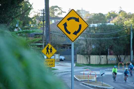 Rotary road sign on a yellow plate on the street.