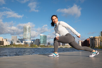 Sporty Woman Stretching Outdoors by the City Waterfront at Sunrise