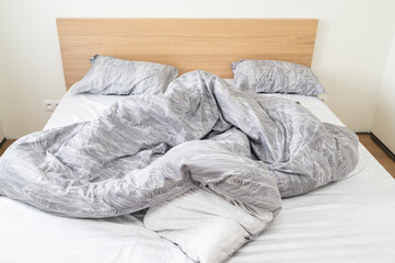 A Cozy Unmade Bed with a Soft Gray Duvet and Plush Pillows, Creating a Peaceful Ambiance