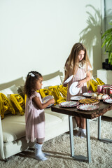 Two little girls are at a table set for a birthday party