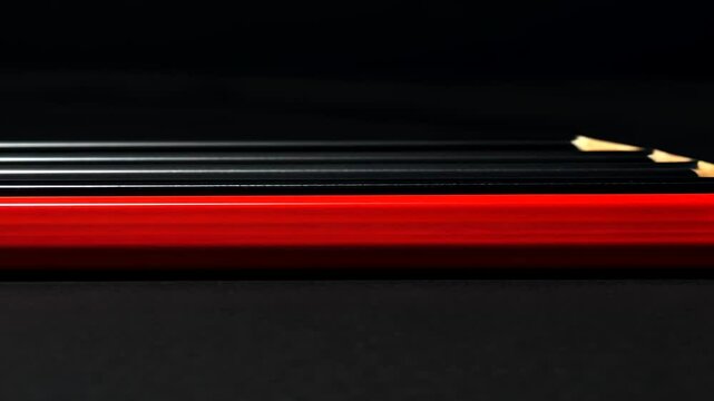 Close-up of multiple red and black pencils against a dark background