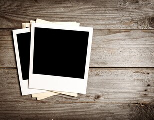 Fototapeta premium Stack of Blank Instant Photos on Weathered Wood Surface with Copy Space