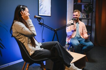 Female podcaster in headphones interviewing man guest using microphone, smiling, recording and...