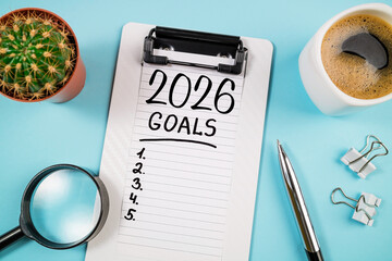New year resolutions 2026 on desk. 2026 goals list with notebook, coffee cup, plant on blue table. Resolutions, plan, goals, action, checklist, idea concept. New Year 2026 resolutions, copy space
