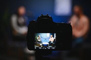 Show host interviewing woman during live stream, talking about fashion and style trends,...