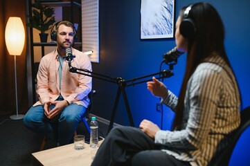 Side view of successful woman hosting podcast interviewing man while recording with professional microphones, copy space