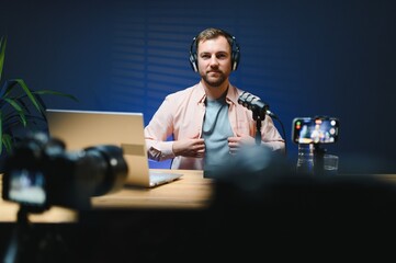 vlogger using smartphone to film podcast in studio. blogger with mobile phone, microphone and...