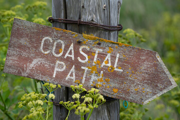 Old sign indicating the direction on a coastal path