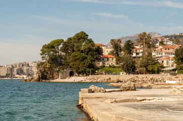 Scenic coastal town in Montenegro with rocky shoreline and pier, nestled among lush greenery