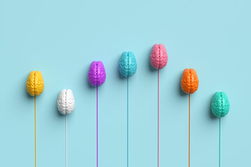 Colorful brains on pastel blue background representing competing ideas or thoughts concept.