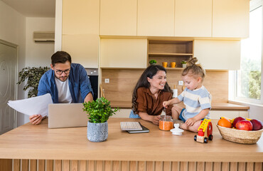 Joyful young family bonding in bright modern kitchen mother and daughter laughing while playing on...