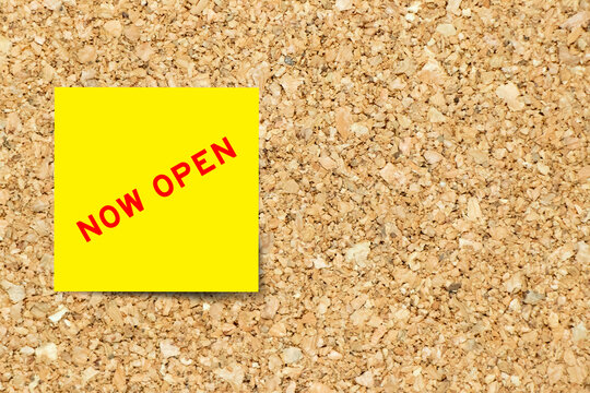 Yellow note paper with word now open on cork board background with copy space