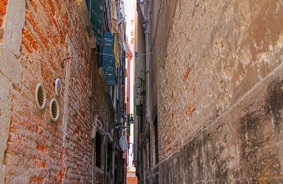Venice, Italy - Narrow street squeezing between decaying buildings in Venice