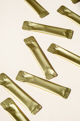 Golden Metallic Stick Packaging on Light Background. Small Packets for Food, Medicine or Cosmetic Product.
