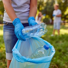 Primer plano de manos con guantes recogiendo basura y botellas de plástico realizando un trabajo medioambiental