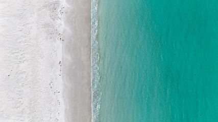 Aerial of clear blue water meeting white sand