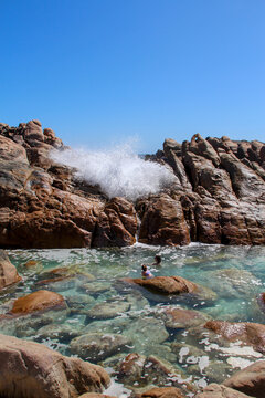 People swimming in natural ocean spa amongst rocks