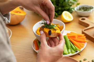 Preparing a healthy snack with pumpkin hummus and fresh vegetables for a nutritious meal