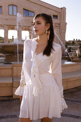 beautiful woman with long dark hair in elegant white dress and accessories posing in elegant antic...