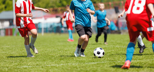 Youth Soccer Match in Action: Kids Competing on Grass Field in Colorful Uniforms During Sunny Day