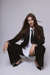 beautiful woman with dark long hair in elegant masculine style suit and tie
