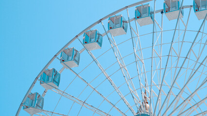Close view of Ferris wheel cabins on sunny sky background in park setting