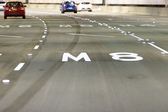 blurred view from a car, Sydney toll road tunnel showing M8 and merging lane signs