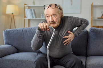 Unhealthy elderly man suffers heart attack at home, grappling with cardiology problem and cramp,...