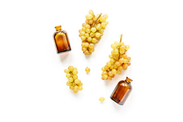 Two bottles of grape seed oil and yellow grapes brunches, top view